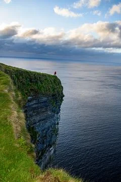 Dramatic stratified rock formations on the coast, green clifftop over the deep b Fotos Stock