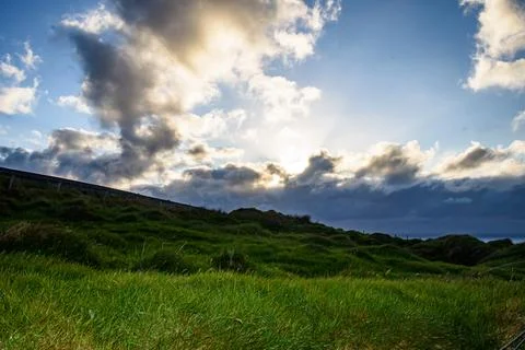 Dramatic stratified rock formations on the coast, green clifftop over the deep b Fotos Stock