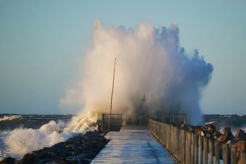 Dramatic, strong waves and foam spray hit the pier on the North Sea coast Stock Photos