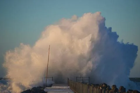Dramatic, strong waves and foam spray hit the pier on the North Sea coast Stock Photos