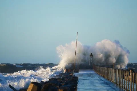 Dramatic, strong waves and foam spray hit the pier on the North Sea coast Stock Photos