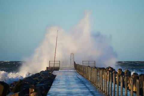 Dramatic, strong waves and foam spray hit the pier on the North Sea coast Stock Photos