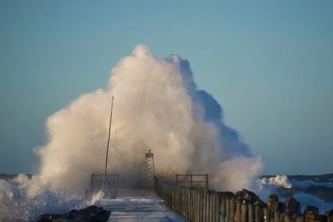 Dramatic, strong waves and foam spray hit the pier on the North Sea coast Stock Photos