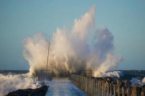 Dramatic, strong waves and foam spray hit the pier on the North Sea coast Stock Photos
