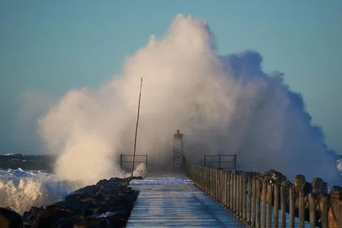 Dramatic, strong waves and foam spray hit the pier on the North Sea coast Stock Photos