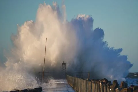 Dramatic, strong waves and foam spray hit the pier on the North Sea coast Stock Photos