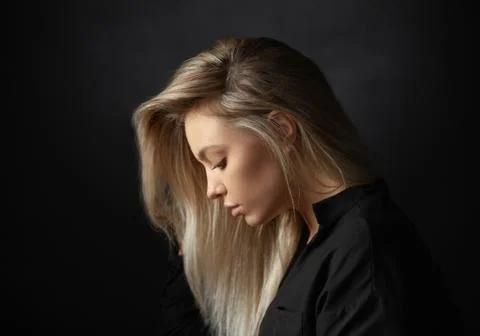 Dramatic studio portrait of beautiful young woman on dark background. Stock Photos