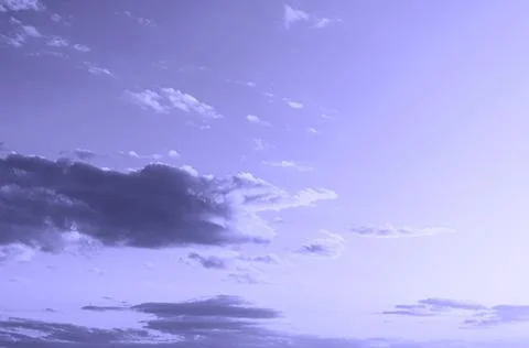 Dramatic summer sky with dark clouds toning very peri color. Stock Photos