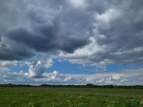 Dramatic summer sky with thunderstorm clouds over field Stock Photos