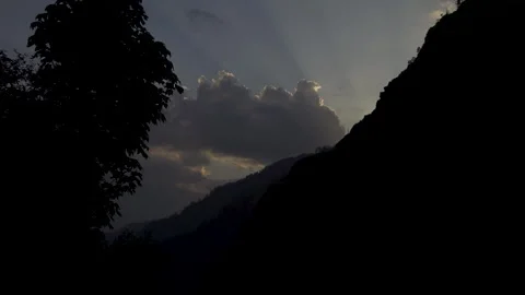Dramatic sun flares from behind mountains at dusk in a valley. Video stock 280261939