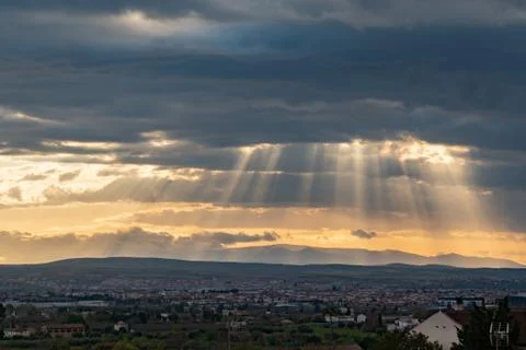 Dramatic sun ray through low clouds over city at sunset. The sun cuts through Stock-Fotos