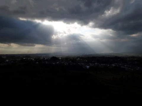 Dramatic Sun Rays Breaking Through Dark Storm Clouds Over Rural Landscape Foto stock