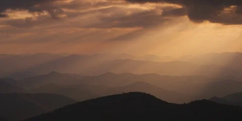 Dramatic sun rays falling on the layers of mountain ranges at sunset Stock Footage 103397826