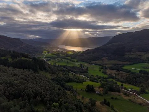 Dramatic Sun Rays Over Green Norwegian Valley and Fjord 스톡 사진