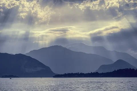 Dramatic Sun Rays Over Serene Mountain Lake at Twilight Stock Photos