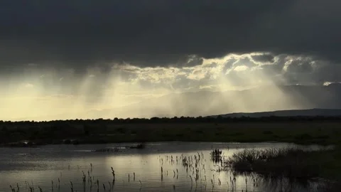 Dramatic Sun Rays Shine Through Dark Clouds Over a Calm Wetland in China Vídeo Stock 336857687