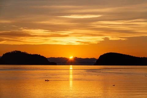 Dramatic sun rising between two hills with water Stock-Fotos