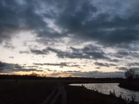 Dramatic sun set night sky countryside side of river Stock Photos
