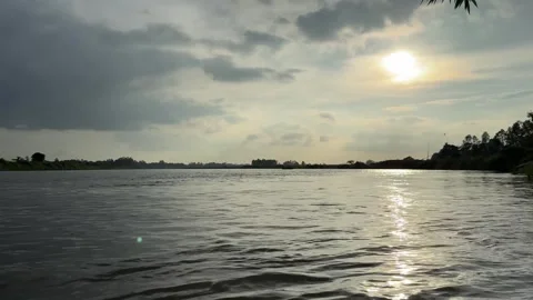 Dramatic sun shining over calm river water under cloudy sky. 4k video 60 fps Stock Footage 340441544
