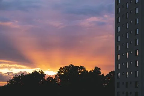 Dramatic sunbeams behind the Residential Building With Reflections in a Windows Stock Photos