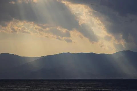 Dramatic sunbeams breaking through clouds over mountains. Photos