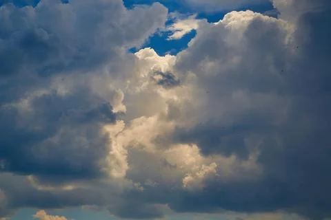 Dramatic sunbeams breaking through cumulus clouds, dense cumulus clouds on bl Stock Photos