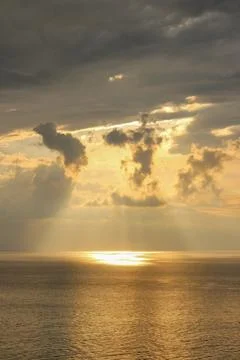 Dramatic Sunbeams Breaking Through Stormy Clouds over Golden Ocean Sunset Stock-Fotos