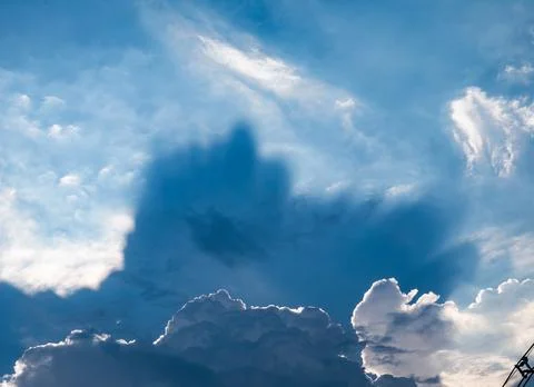 Dramatic sunbeams breaking through white cumulus clouds in deep blue sky cr.. 스톡 사진