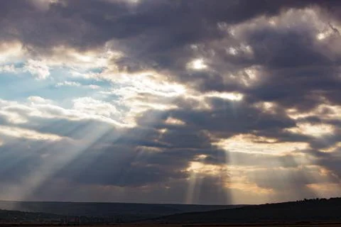 Dramatic sunbeams shining through storm clouds over rural landscape Fotos Stock