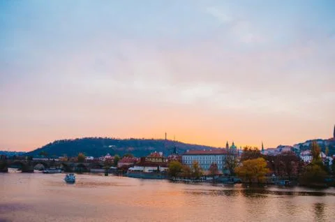 Dramatic sundown in the Vltava River with a boat passing by and a gradient of Stock Photos