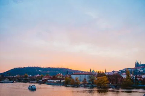 Dramatic sundown in the Vltava River with a boat passing by and a gradient of Stock Photos