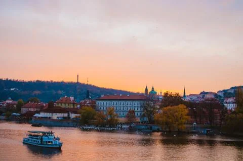 Dramatic sundown in the Vltava River with a boat passing by and a gradient of Stock Photos