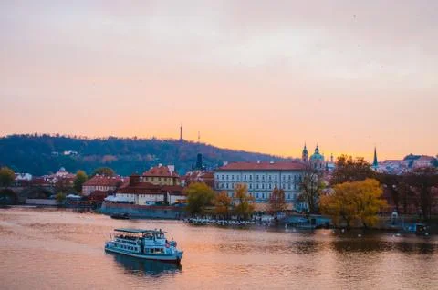Dramatic sundown in the Vltava River with a boat passing by and a gradient of Stock Photos