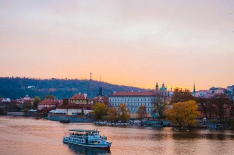 Dramatic sundown in the Vltava River with a boat passing by and a gradient of Stock Photos