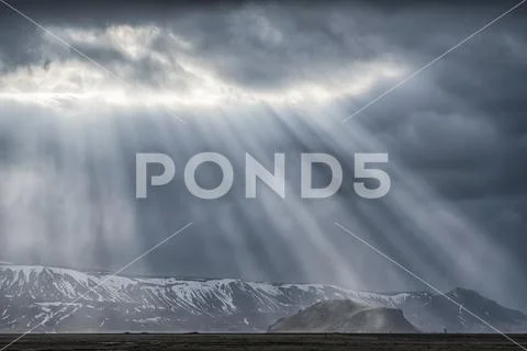 Dramatic sunlight beams punch through the clouds along the South coast of Icelan Stock Photos