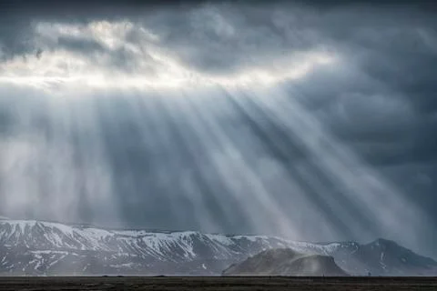 Dramatic sunlight beams punch through the clouds along the South coast of Icelan Stock Photos