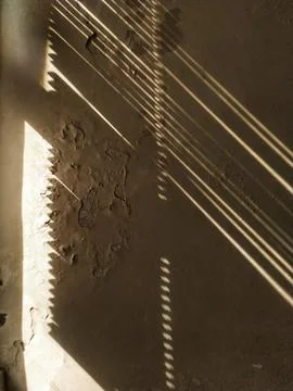 Dramatic sunlight patterns cast by blinds on textured wall Stock Photos