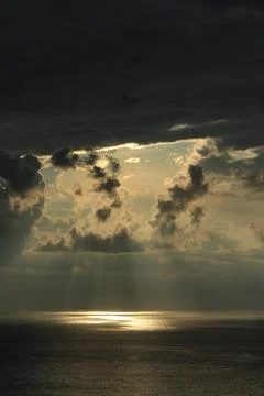 Dramatic Sunlight Rays Breaking Through Storm Clouds Over Ocean Stockfoto's