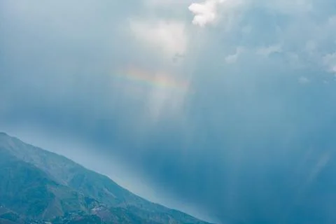 Dramatic sunlight rays piercing through heavy storm clouds above the rugged m 库存照片