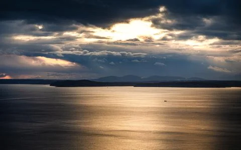 Dramatic sunlight through cloudy sky over sea surface, Seattle, USA. Stock Photos