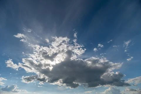 Dramatic sunlit cloudscape with rays breaking through blue sky Stockfoto's