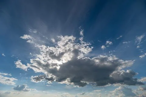 Dramatic sunlit cloudscape with sunbeams breaking through blue sky Stock Photos