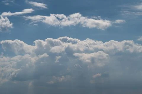 Dramatic sunlit cumulus clouds with layered sky and light rays Stock Photos