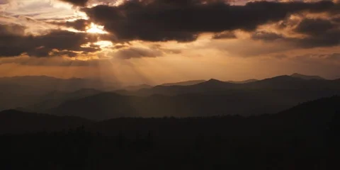 Dramatic sunrays falling on the silhouetted mountain ranges at sunset Stock Footage 103397895