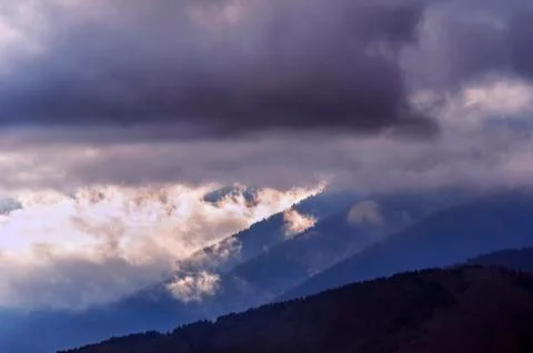 Dramatic Sunrise in the Mountains with Cloudy Sky and Misty Forest Stock Photos