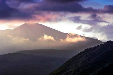 Dramatic Sunrise in the Mountains with Cloudy Sky and Misty Forest Stock Photos