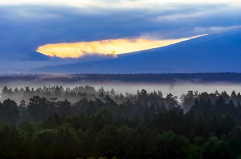 Dramatic Sunrise in the Mountains with Cloudy Sky and Misty Forest Foto stock