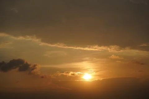 Dramatic sunrise over misty rural landscape with scattered clouds and golden Stock Photos
