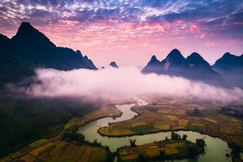 Dramatic sunrise over mountain range with foggy on rural village and river .. Stock Photos