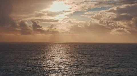 Dramatic sunrise over the ocean. A ray of the sun breaks through the clouds Stock Photos